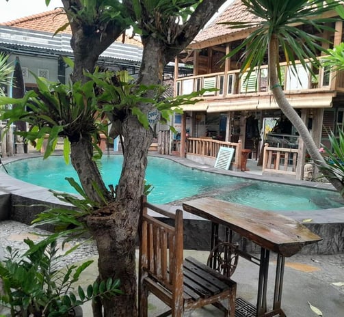 a pool with a wooden table and chairs view in sunrise lodge lovina bali 