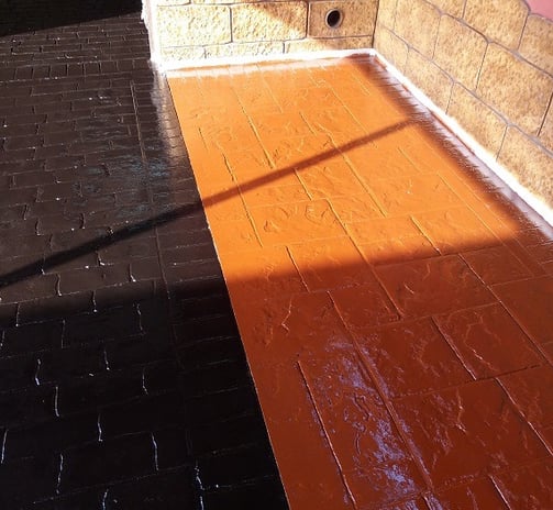 Superficie de hormigón impreso con acabado en resina de dos colores, ideal para crear contraste en áreas exteriores.
