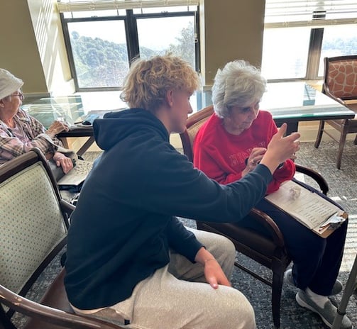 boy helping elderly woman learn how to add a new app on with her iphone
