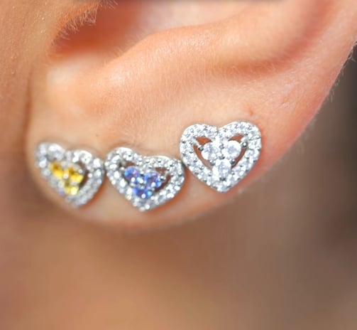 a close up of a pair of ear piercings with a heart shaped diamond