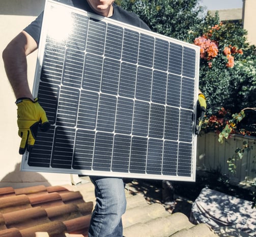 A man displaying the front surface of a solar panel during the installation process