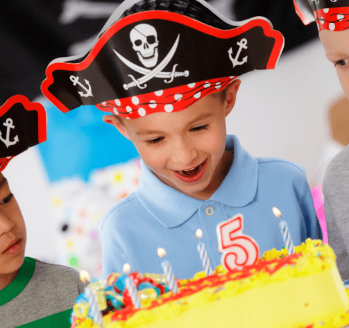 Un enfant déguisé en pirate devant son gâteau d'anniversaire