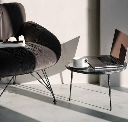 a laptop computer sitting on a table next to a chair with a smartphone on the seat