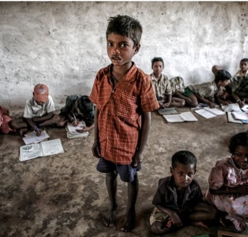 a boy standing in front of a group of children in a class room