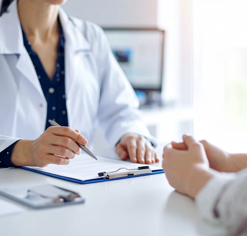 Médico mujer dando consulta con pluma en la mano