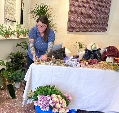 a woman is standing in front of a table with flowers