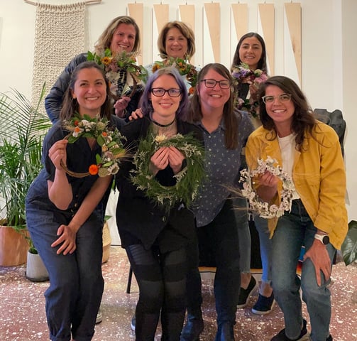 a group of women standing and showcasing wreaths