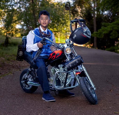 niño comunion montado en su moto  roja y  negra        