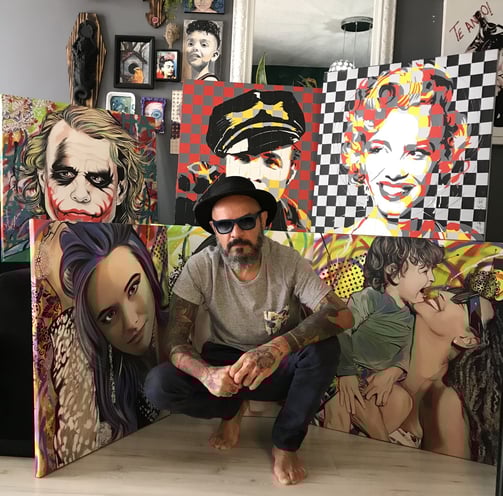 Retrato de Sérgio Astral posando ao lado de sua arte contemporânea em uma galeria.