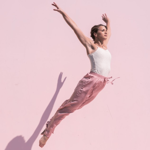 Dancer jumping against a pink backdrop.