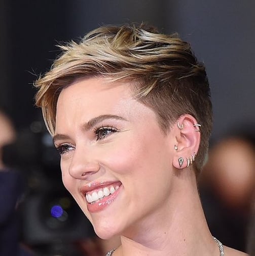 Close-up de mulher com corte de cabelo Pixie em tom platinado e raiz escura.