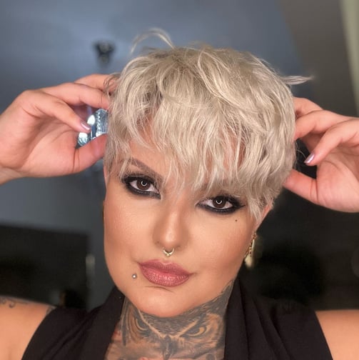Close-up de mulher com corte de cabelo Pixie em tom platinado e raiz escura.