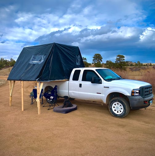 A truck with a fold-out overlanding tent on it's bed