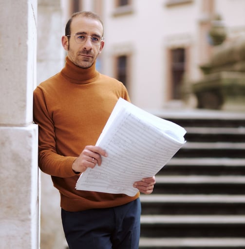 Leonardo Rizzo in a turtle neck sweater holding a piece of paper