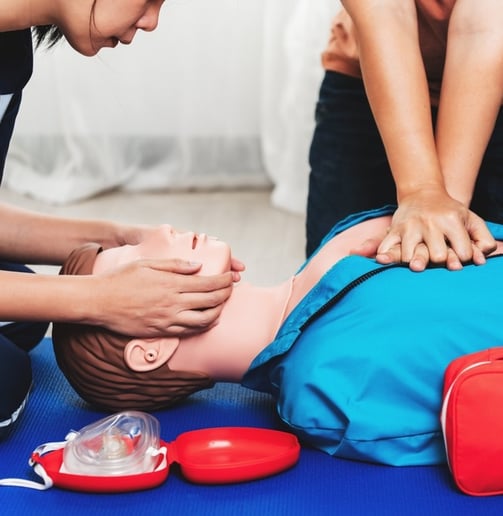 Two people practising CPR on a dummy in First Aid training