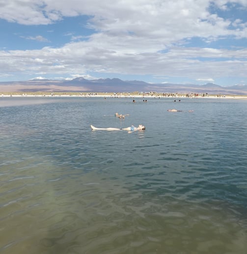 Mujer madre flotando boca arriba sin esfuerzo en laguna Cejar en Atacama Chile