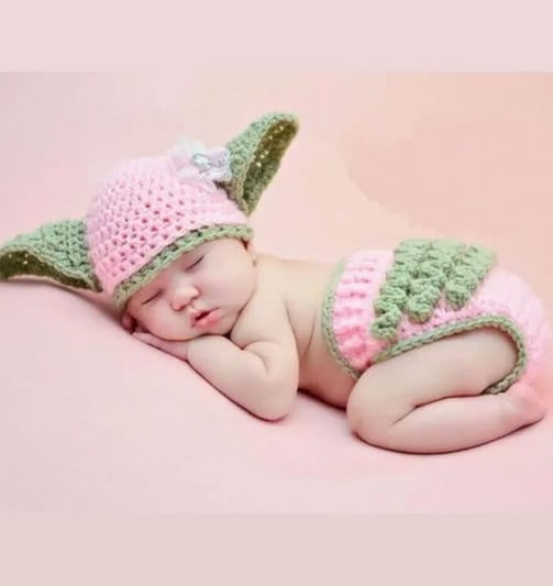 a baby yoshi is wearing a pink and green hat