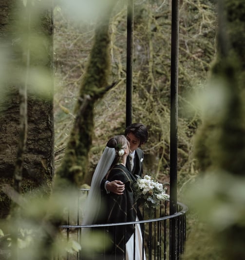 a bride and groom kissing on a bridge