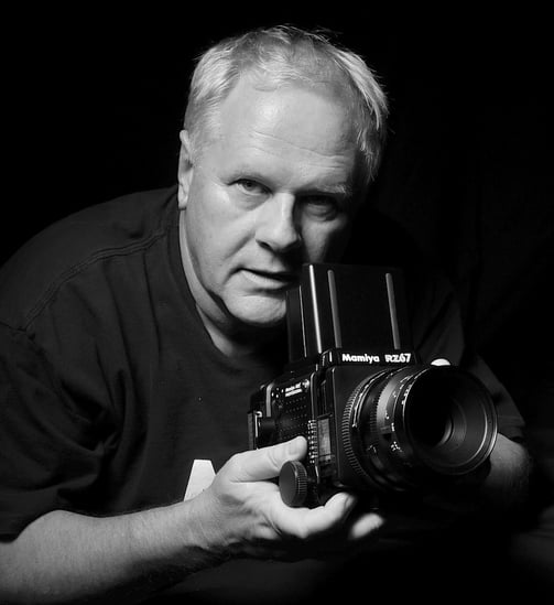 Peter Pickering, photographer, holding a Mamiya medium format camera and taking a picture