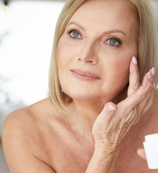 woman putting cream on her wrinkles