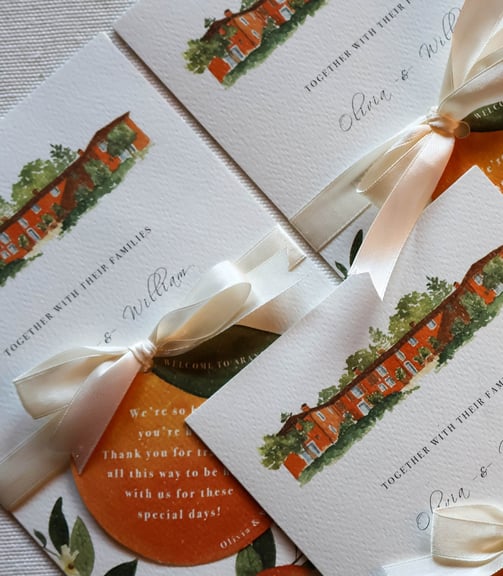 close up on invitation with orange cutout welcoming guests to the event white ribbon