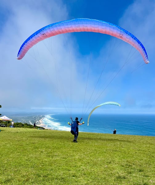 a person is parasailing over a grassy field