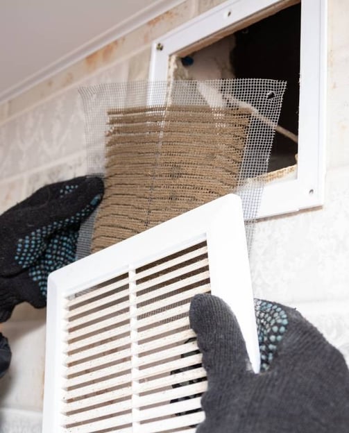 a person wearing gloves and gloves is cleaning a vent vent venting