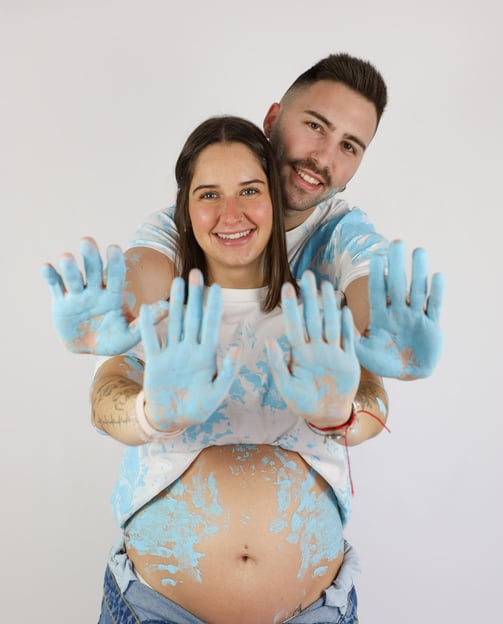 Sessió de fotos de gender reveal a Girona d'una parella amb pintura blava en estudi fotogràfic