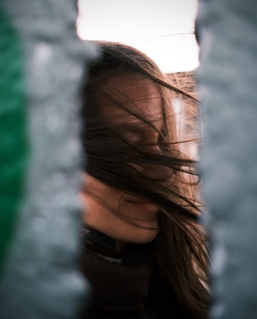 a woman with long hair and a black jacket. wind is blowing in the hair.