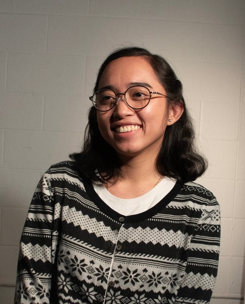 Portrait of Fatima Fabillar, smiling and wearing a patterned cardigan against a neutral background
