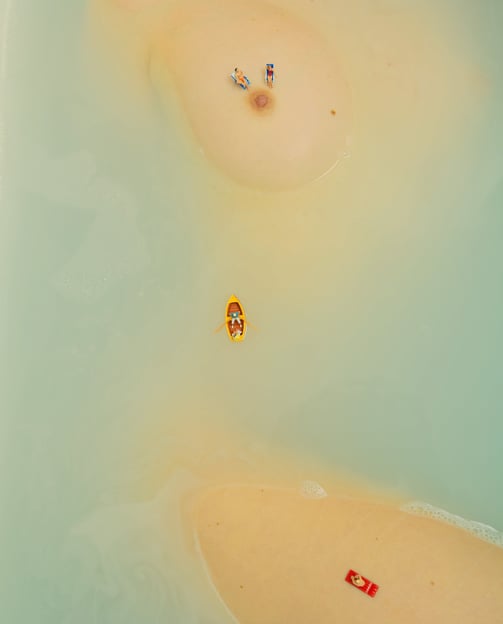 a person in a bathtub with a small boat in the water