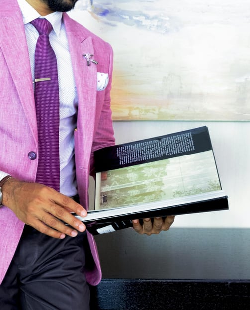 a man in a pink suit and tie is holding a book