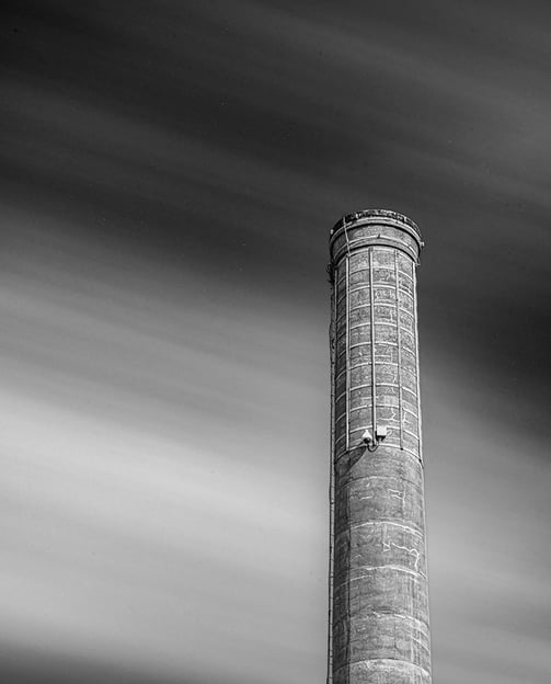 Prominent Georgetown Tx smokestack stands against a streaked cloud sky
