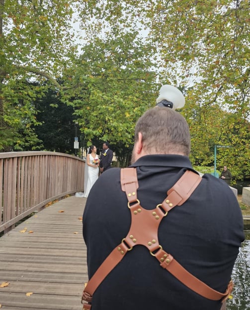 A Hertfordshire bride & groom standing on a wooden bridge over a river, the bridge is sorrounded by trees in autumnal colour 