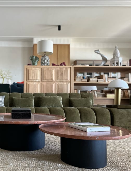 Contemporary lounge at Villa La Gratitud with velvet sofas, round marble tables, and bookshelves.