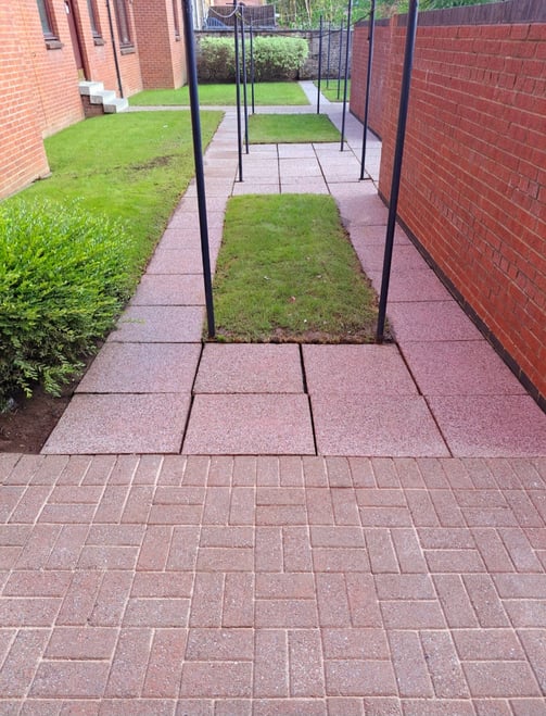 a back court with red monoblock bricks, red concrete slabs and black washing poles