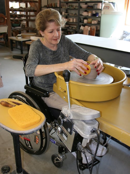 Woman in a wheelchair throwing on our wheelchair-accessible potter's wheel.