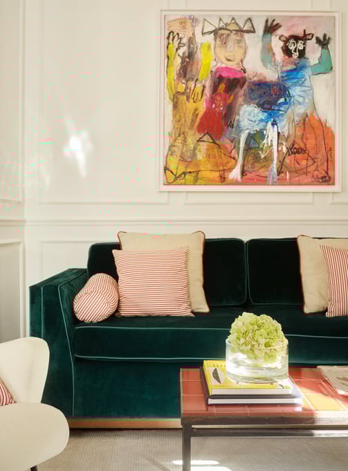 Salon haussmannien rénové à Paris avec moulures, canapé vert en velours sur mesure et œuvres d’art
