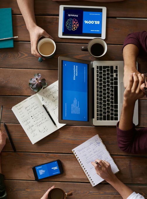 a group of people sitting at a table with laptops