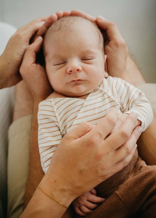 Bébé endormi dans les mains de ses parents – photo naissance à domicile Gard