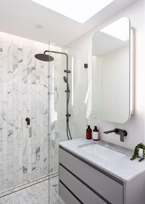 Contemporary bathroom interior with a grey vanity, mirrored wall cabinet, glass-enclosed shower