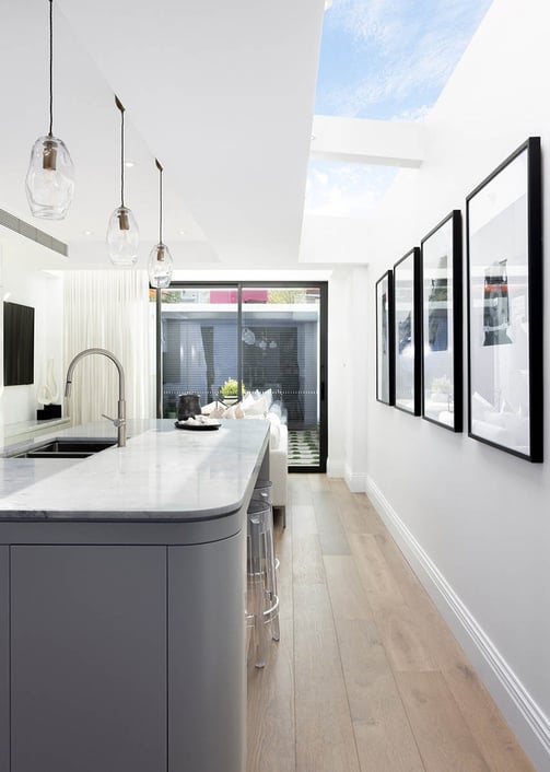 Stylish kitchen island with skylight above, oak flooring, contemporary interior design, modern art
