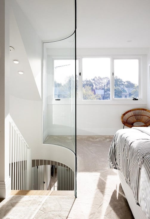 Modern attic bedroom featuring a custom-made curved glass wall panel, blending architectural design