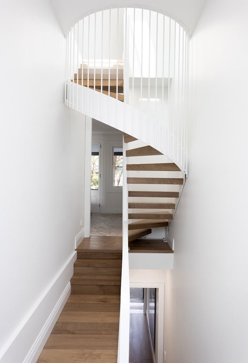 Minimalist interior featuring metal spiral staircase with timber treads, white walls, clean design