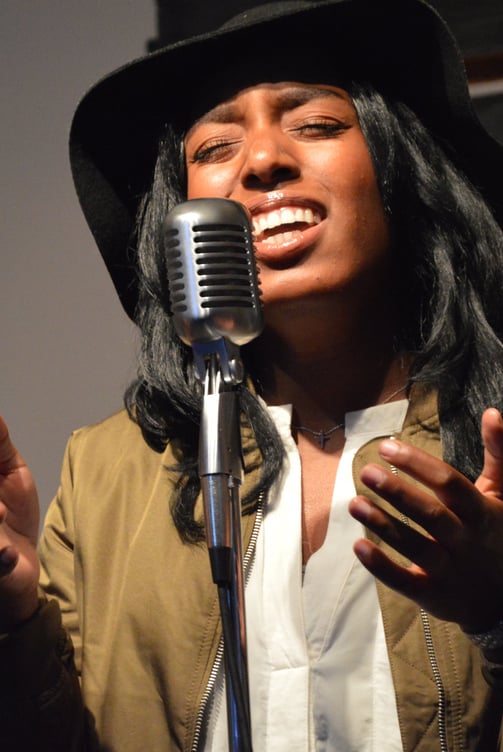 a woman in a hat and a hat singing into a microphone