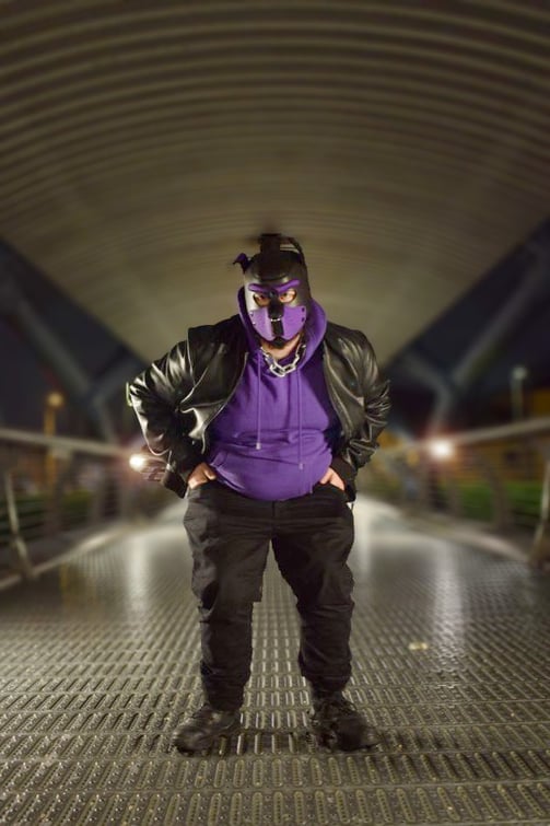 A man in a pup mask outdoors at night.