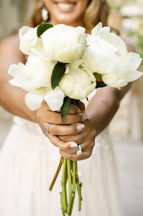 Bridal bouquet held by the bride with a soft-focus smile in the background, Provence elopement