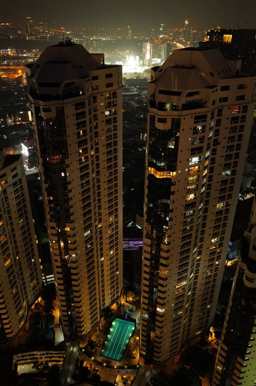 Night aerial view of twin towers in bangkok with pool below, By ACAT Photos