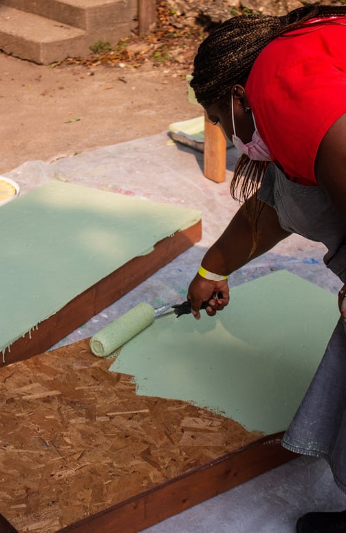 Volunteer painting benches with a roller.