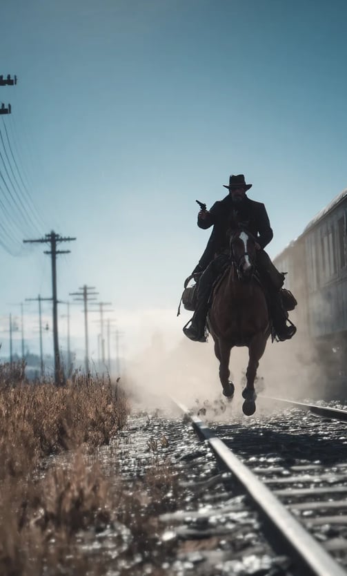 Jesse James gallops alongside the moving train, his black coat flapping